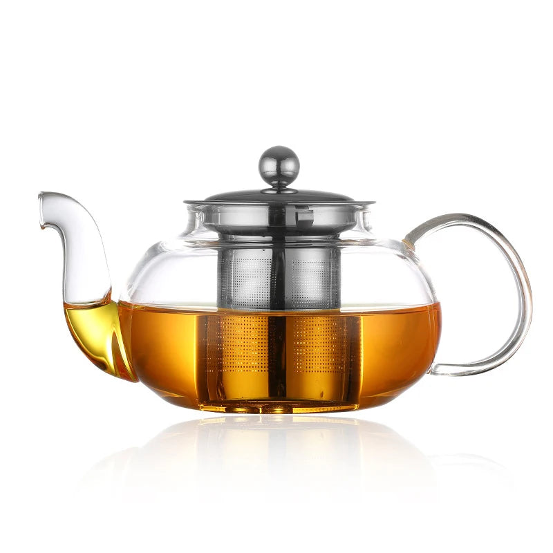 Wide glass teapot with steel infuser and amber tea, on a white background