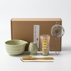 Sage matcha gift set on a light background: bowl, whisk holder, bamboo whisk, scoop and spoon, steel sieve and kraft box