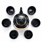 Black tea set seen from above: the teapot in the centre, surrounded by six cups