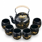 Black tea set with the gold village motif, showing small houses among trees, on a white background