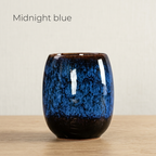 Midnight blue glazed tea cup with a deep blue speckled glaze, on a light oak table