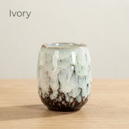 Ivory glazed tea cup in creamy white with a dark base, on a light oak table