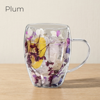 Plum design: glass cup with dried purple flowers and a yellow accent, on a light oak table
