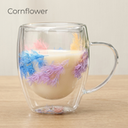 Cornflower design: glass cup with dried blue and mauve flowers, filled with milk, on a light oak table