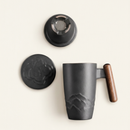 Black tea mug seen from above with its lid and ceramic infuser set beside it