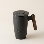 Black ceramic tea mug with lid, wooden handle and mountain relief