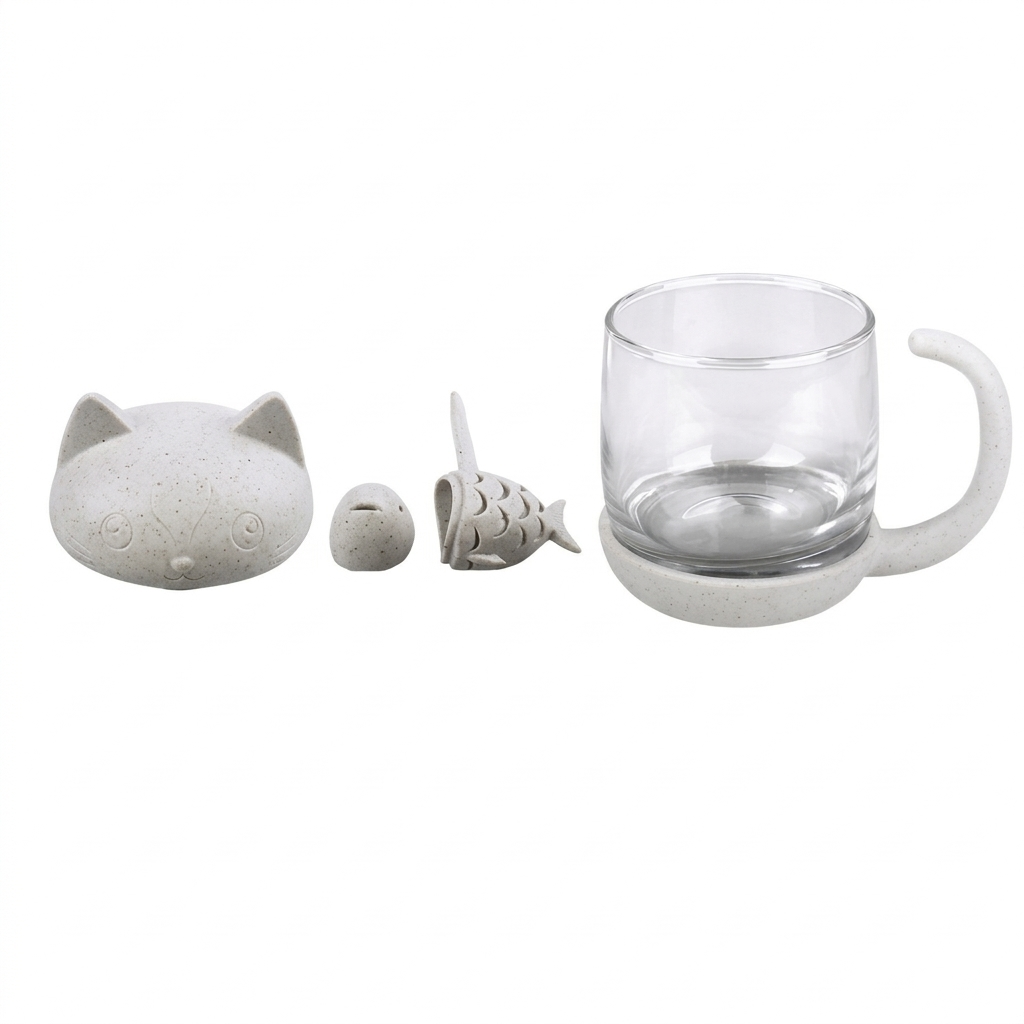 The cat-shaped lid, the fish infuser and the glass mug laid out side by side