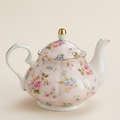 Pink English ceramic teapot with a rose pattern and gold-coloured trim, on a warm beige background