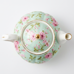 Green rose-pattern teapot seen from above, showing the round lid with its gold-coloured rim